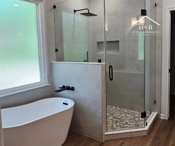 bathroom remodeling in Austin TX A modern bathroom featuring a freestanding white soaking tub with a wall-mounted black faucet.