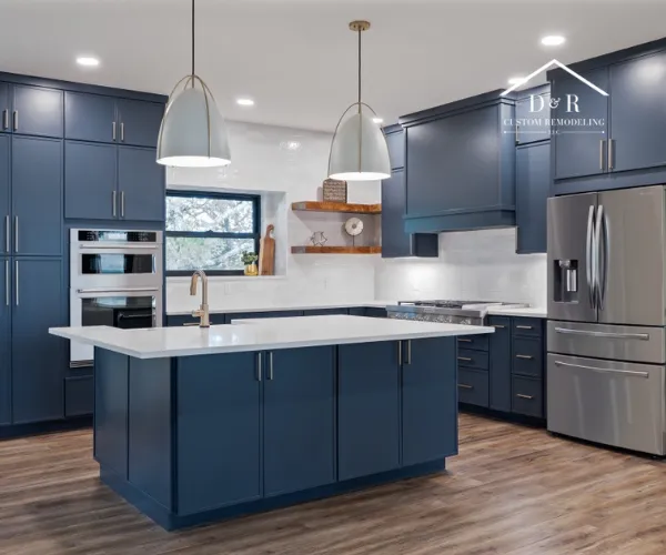 A modern kitchen featuring a large white marble island with blue velvet stools.