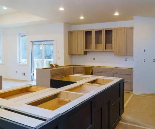 An in-progress kitchen remodel featuring installed dark blue base and pantry cabinets alongside unfinished light wood cabinetry