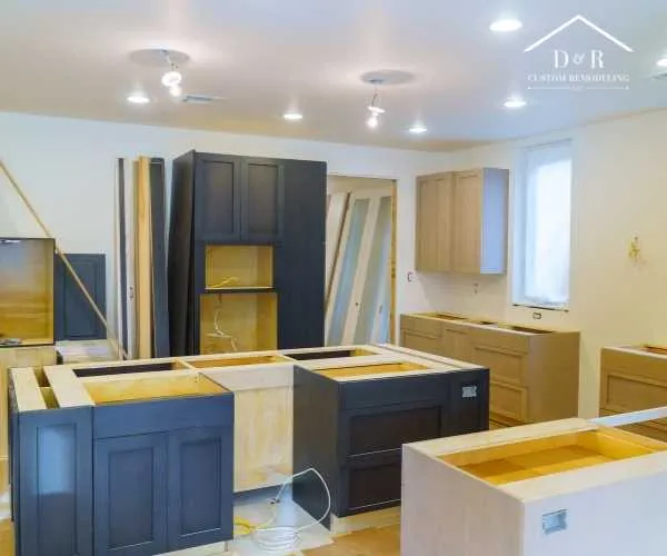 home remodeling in Austin TX An in-progress kitchen remodel featuring installed dark blue base and pantry cabinets alongside unfinished light wood cabinetry