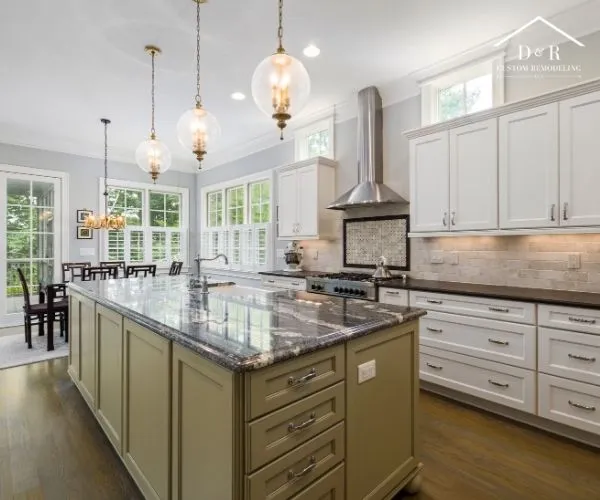 Spacious kitchen featuring a large sage green island with a polished dark marble countertop, white perimeter cabinets, and glass globe pendant lights.